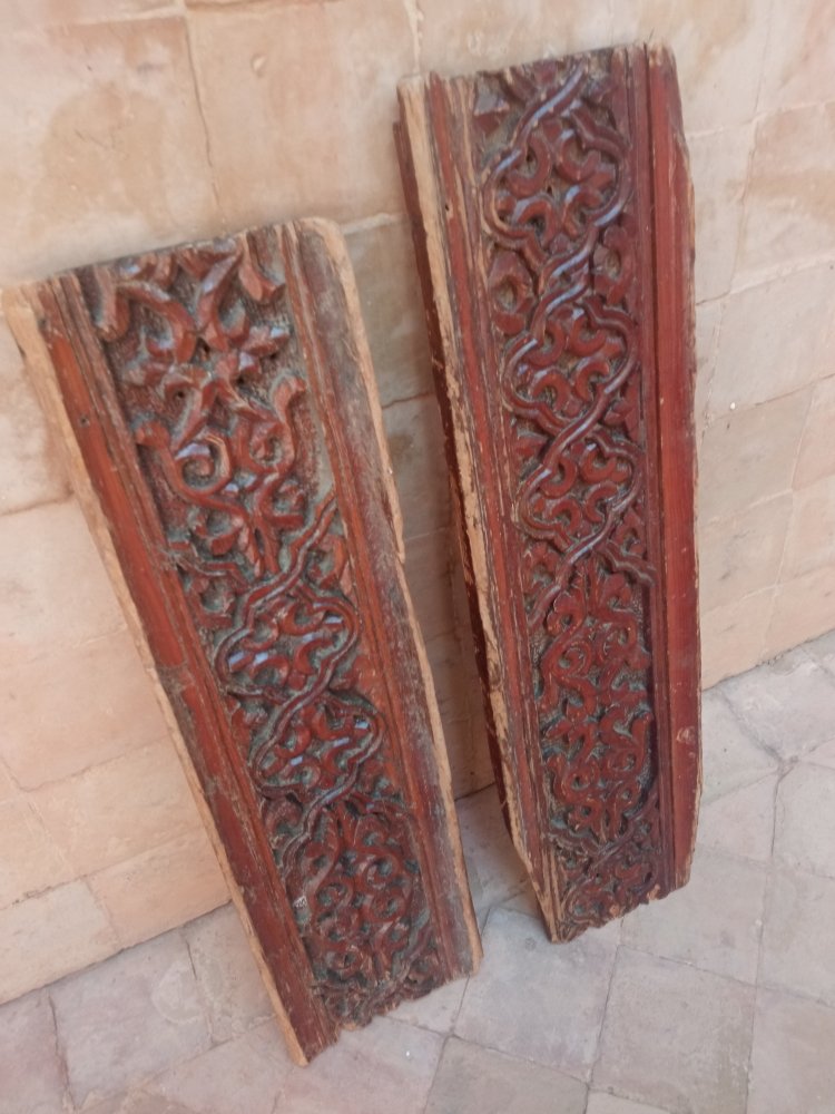 Two wooden panels with intricate carvings on a stone floor.