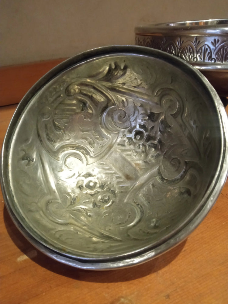 Silver bowl with intricate designs on a wooden surface