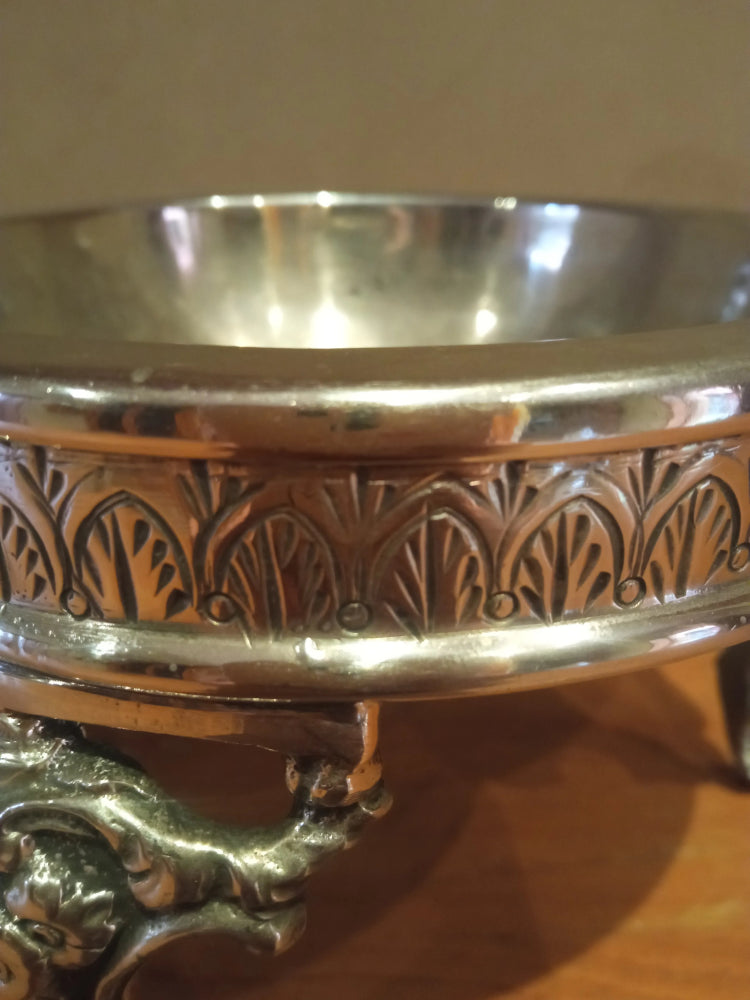 Silver bowl with intricate designs on a reflective surface