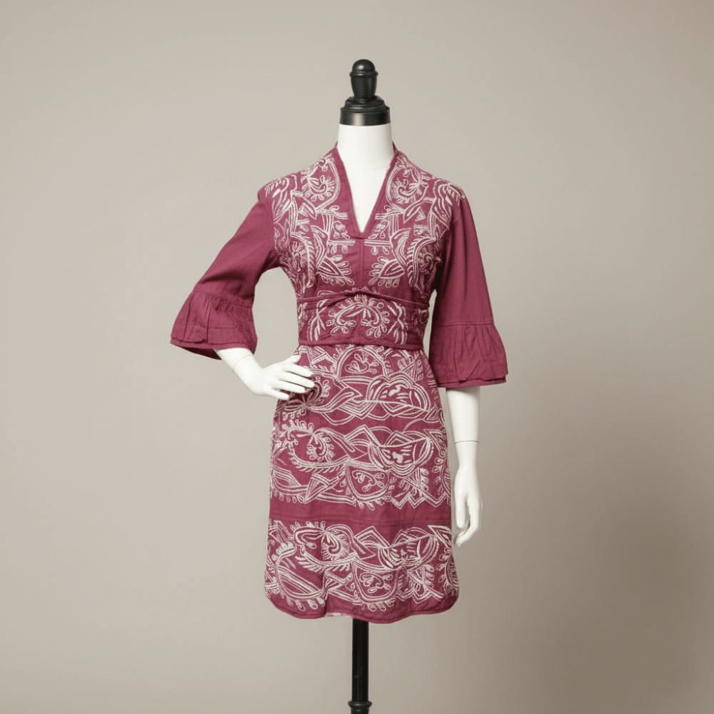 Maroon dress with white pattern on a mannequin against a beige background