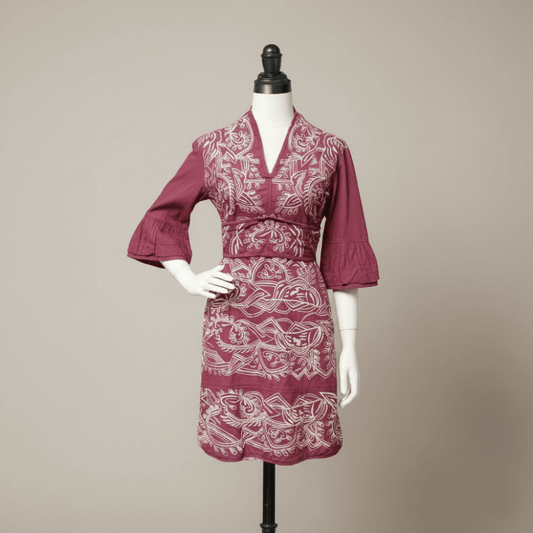 Maroon dress with white pattern on a mannequin against a beige background