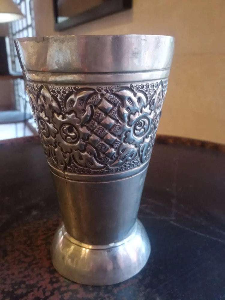 Silver cup with intricate patterns on a dark surface