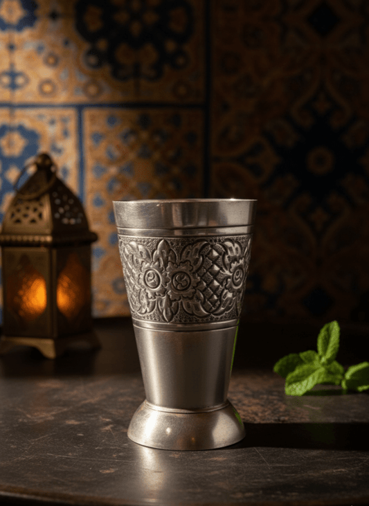 Decorative silver cup on a wooden surface with a patterned wall in the background