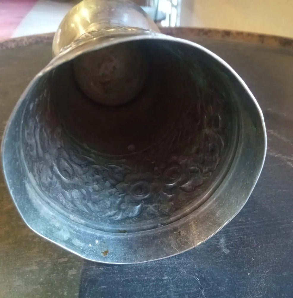 Metallic object with intricate design on a reflective surface