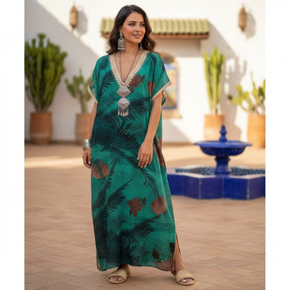 Woman in a green gandoura standing in a decorative outdoor setting with plants and a fountain.