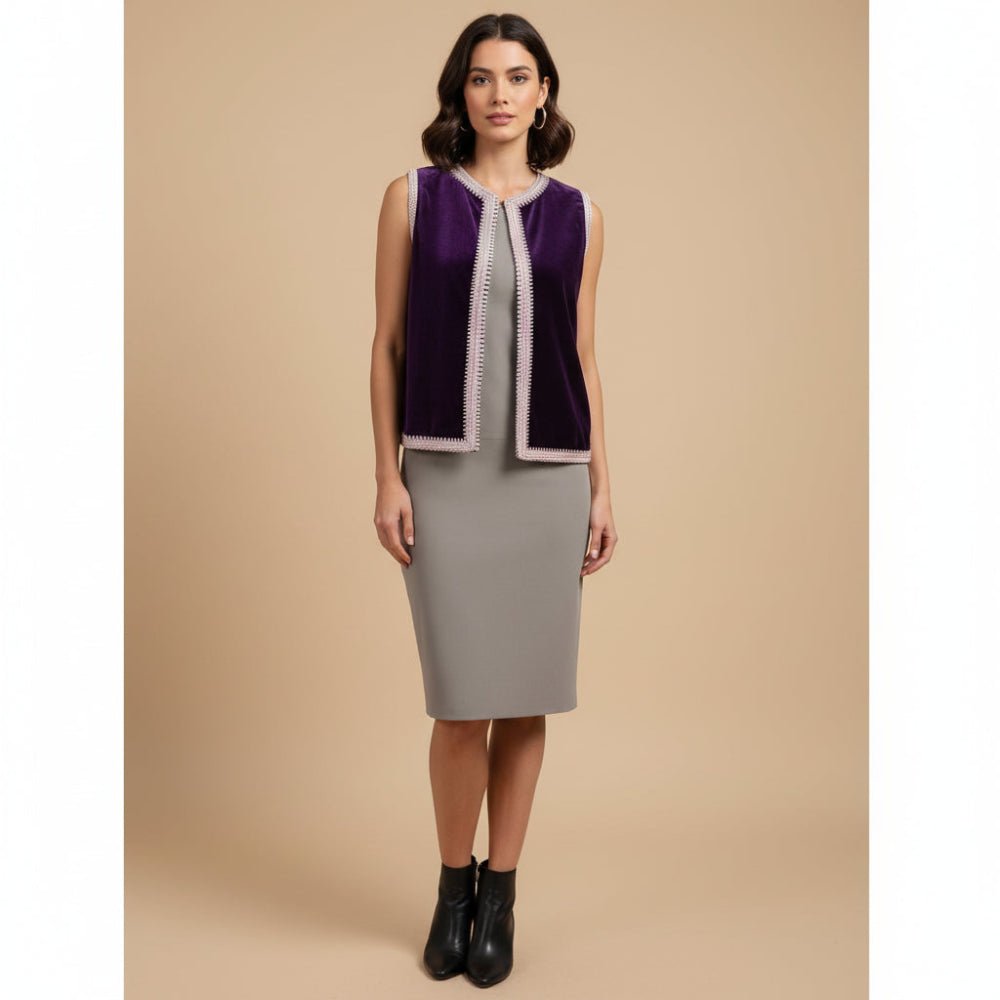 Woman wearing a sleeveless purple top with a patterned trim and a gray skirt on a beige background