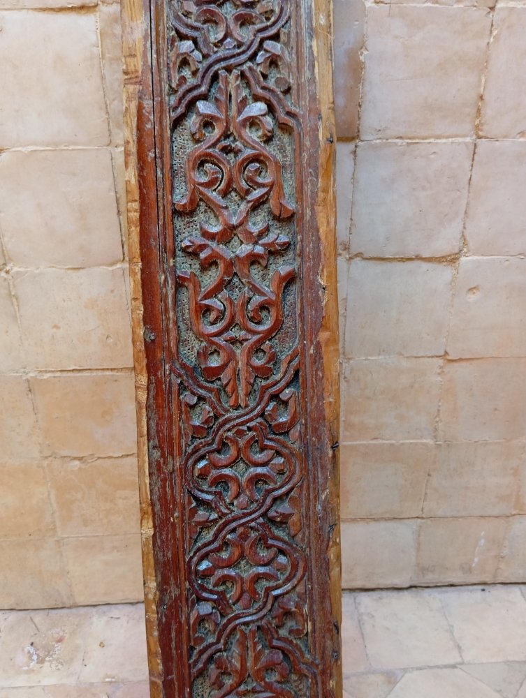 Decorative wooden panel with intricate carvings on a stone wall background