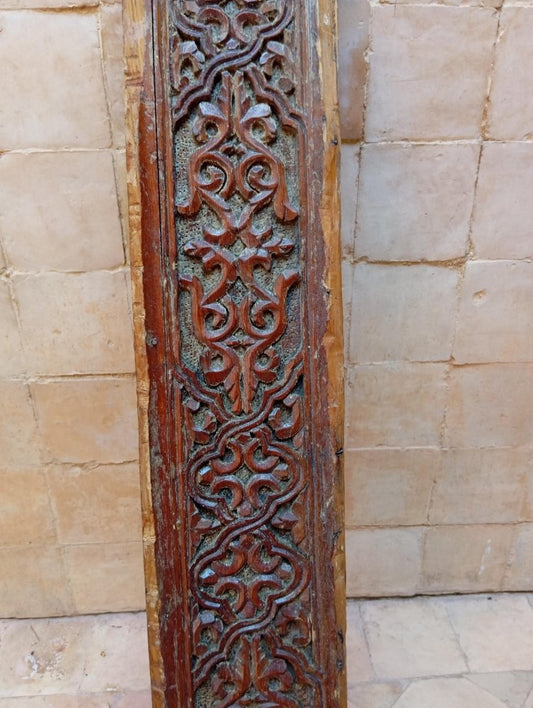 Decorative wooden panel with intricate carvings on a stone wall background