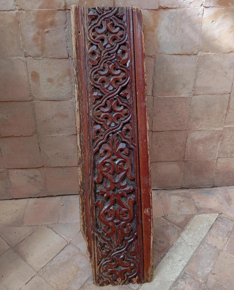 Carved wooden panel with intricate patterns on a stone wall background