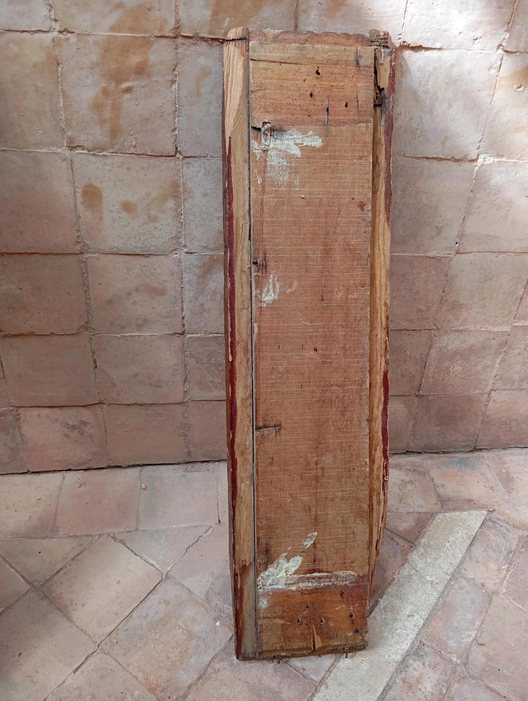 Old wooden panel leaning against a textured stone wall.