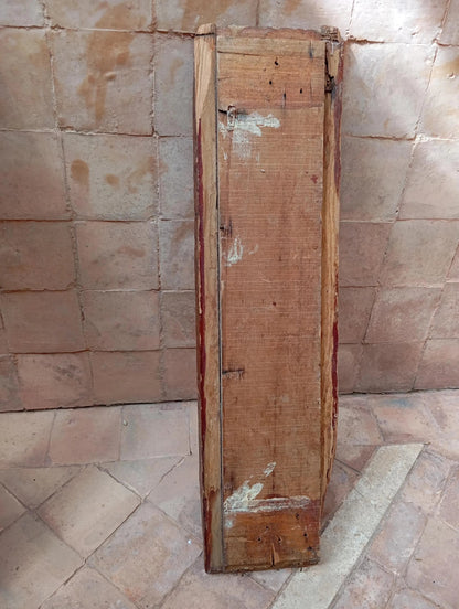 Old wooden panel leaning against a textured stone wall.