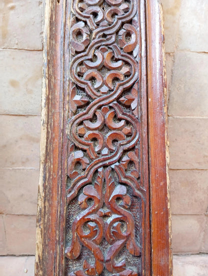 Carved wooden panel with intricate patterns on a stone wall background