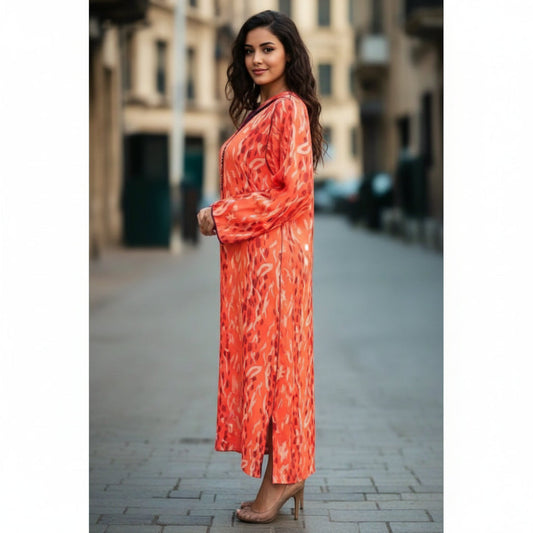 Woman wearing an orange patterned dress standing on a city street.