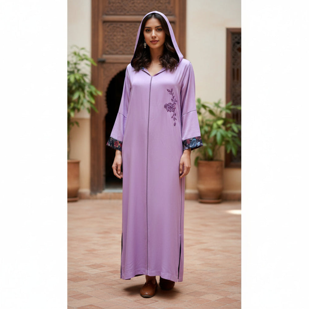 Woman wearing a long lilac moroccan handmade djellaba dress with floral embroidery in an outdoor setting.