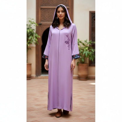 Woman wearing a long lilac moroccan handmade djellaba dress with floral embroidery in an outdoor setting.