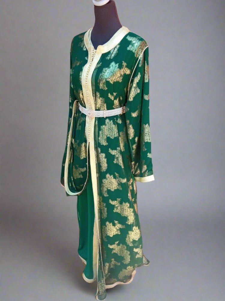 Green and gold patterned dress on a mannequin against a red wall.