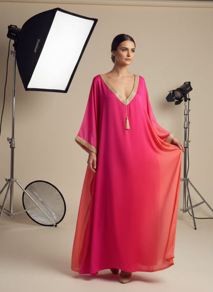 Model wearing a pink gandoura dress in a photo studio setting with lighting equipment.
