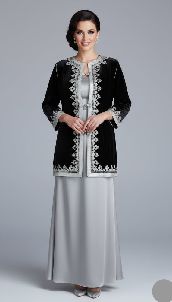 Woman wearing a black embroidered jacket over a silver dress on a gray background