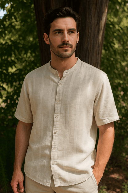 Man wearing a beige shirt standing outdoors with trees in the background
