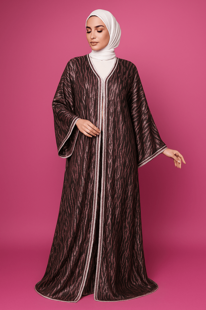 Woman wearing a long, patterned dress with a hood against a pink background