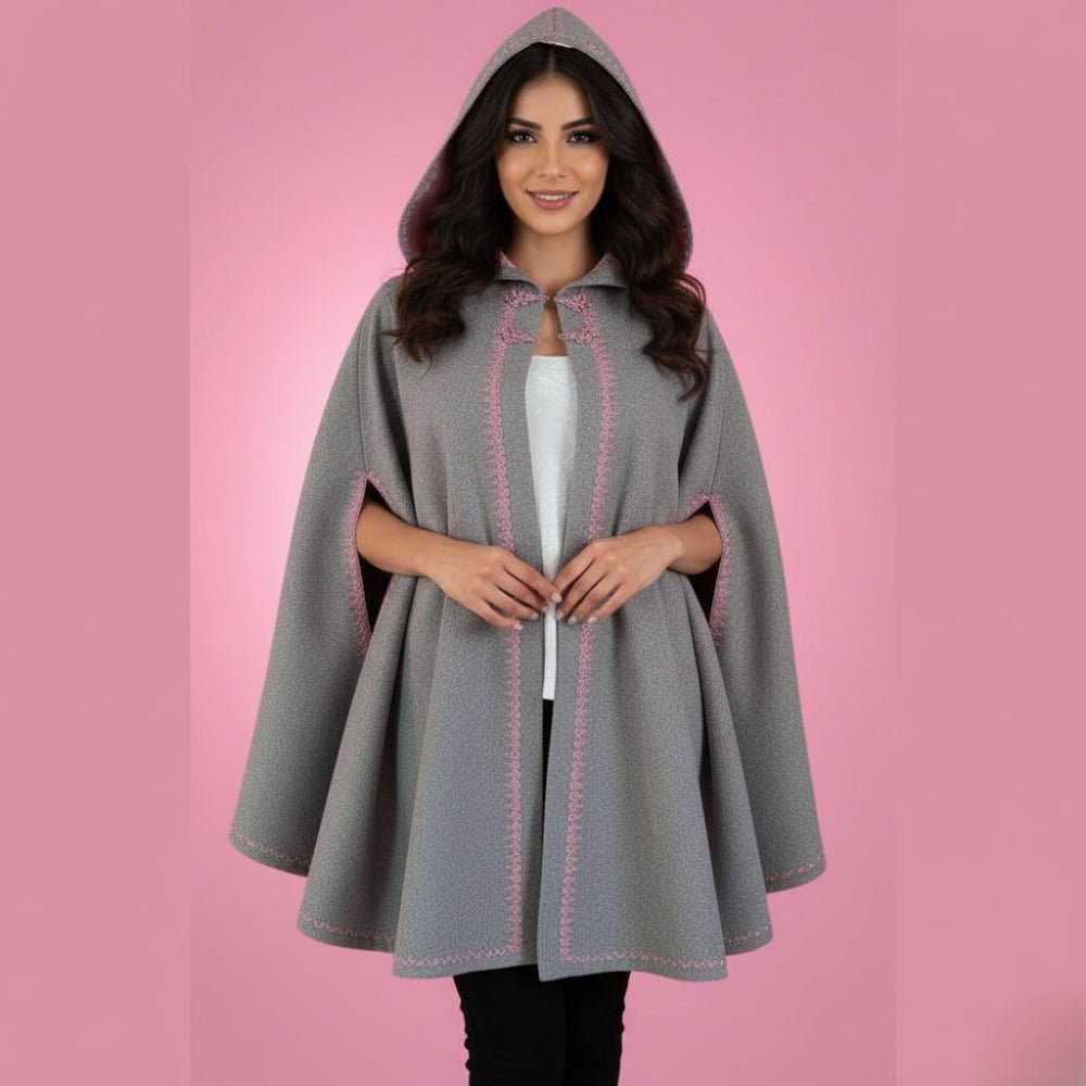 Woman wearing a gray hooded cape with pink stitching on a pink background