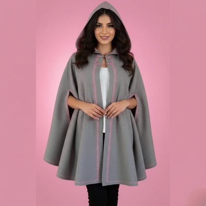 Woman wearing a gray hooded cape with pink stitching on a pink background