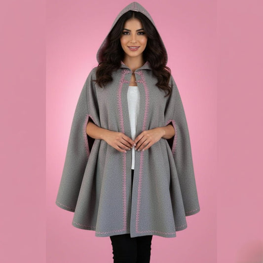 Woman wearing a gray hooded cape with pink stitching on a pink background