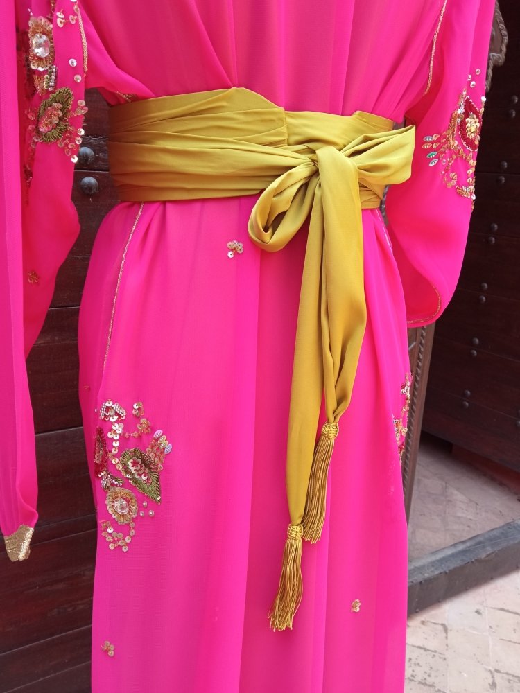 Pink traditional outfit with gold embroidery and a green belt.