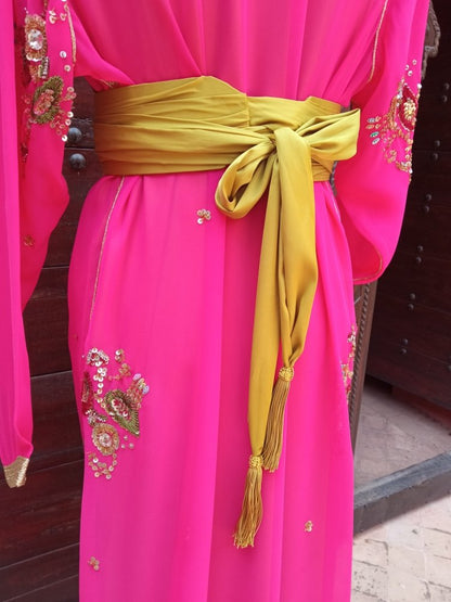 Pink traditional outfit with gold embroidery and a green belt.