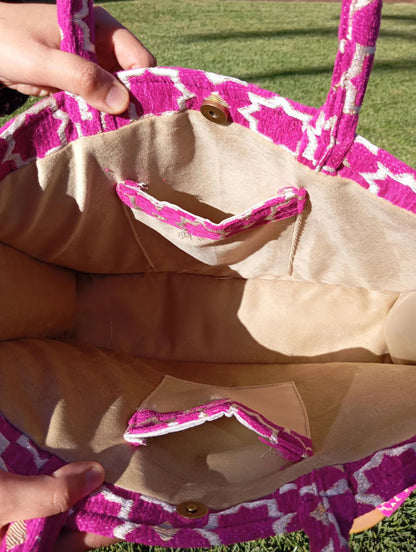 Close-up of a pink and beige bag with a button on a grassy background