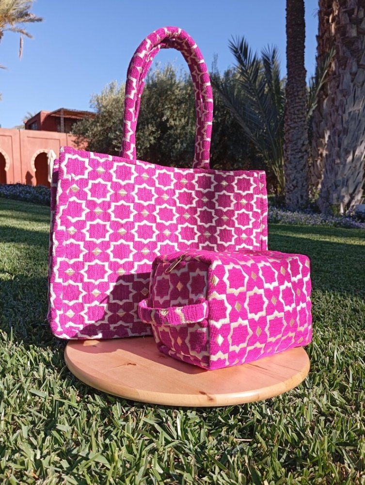 Pink patterned tote bag and small pouch on a wooden stand outdoors.