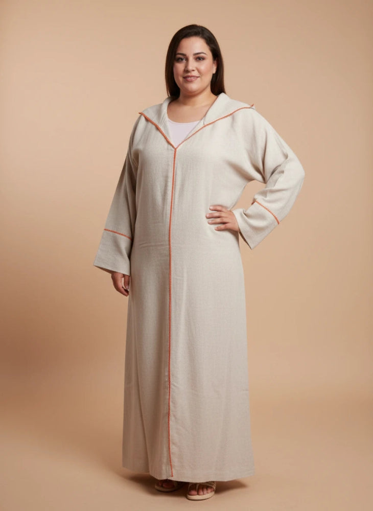 Woman wearing a beige Moroccan djellaba with orange trim on a beige background
