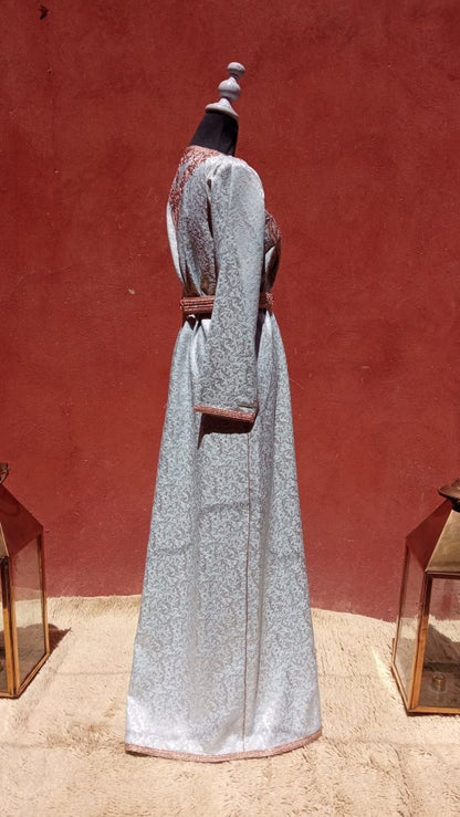 Person wearing traditional Moroccan kaftan attire with a red background