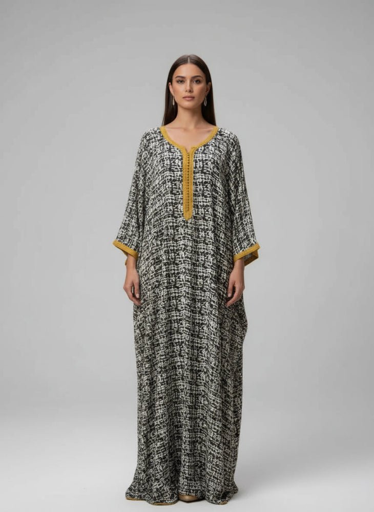 Woman wearing a long, patterned dress moroccan gandoura with yellow accents in a decorative interior setting.