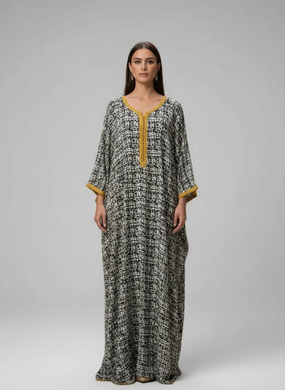 Woman wearing a long, patterned dress moroccan gandoura with yellow accents in a decorative interior setting.