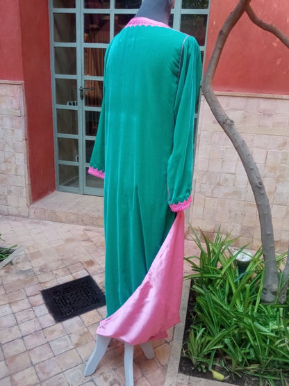 Green and pink dress on a mannequin outdoors against a building and tree.