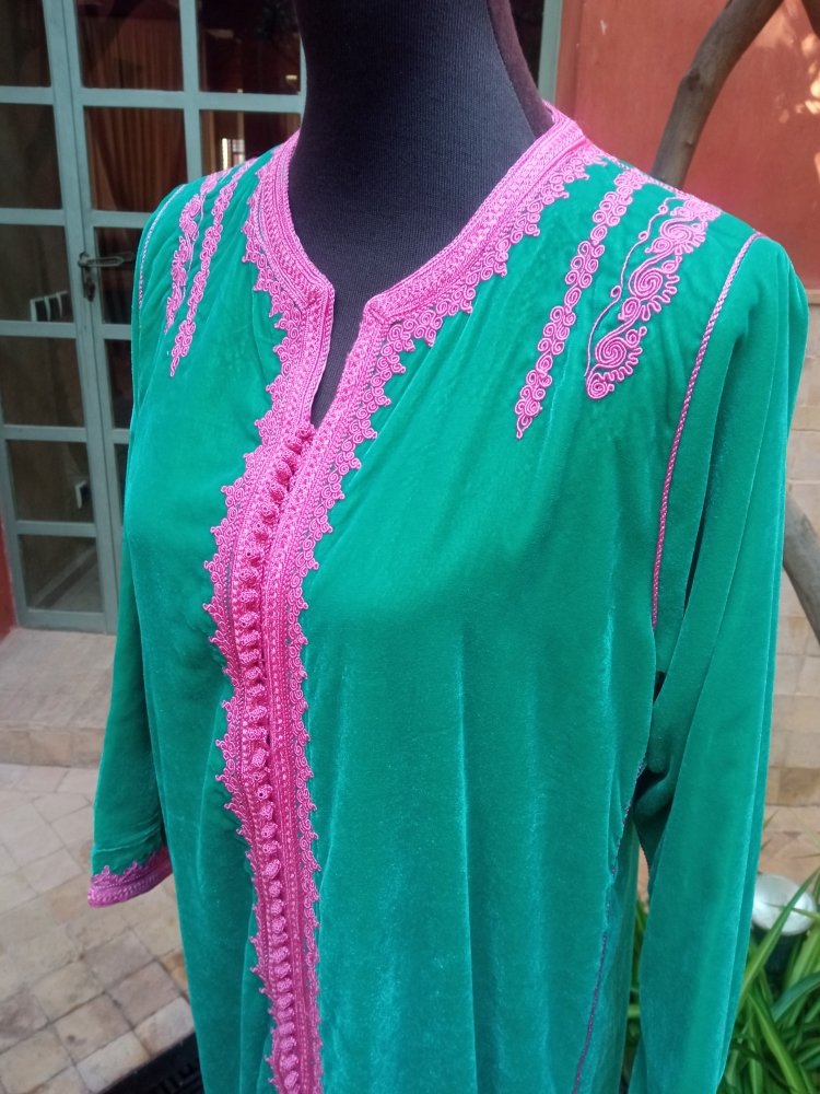 Green dress with pink embroidery on a mannequin against an outdoor background