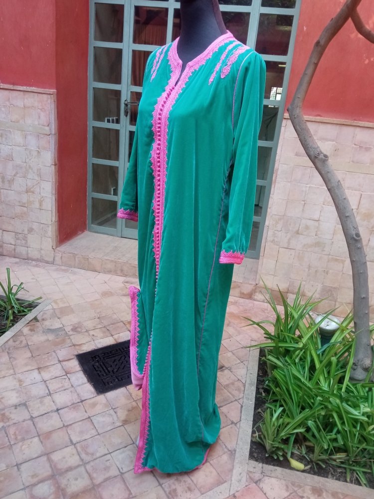 Green dress with pink trim on a mannequin against a building exterior.