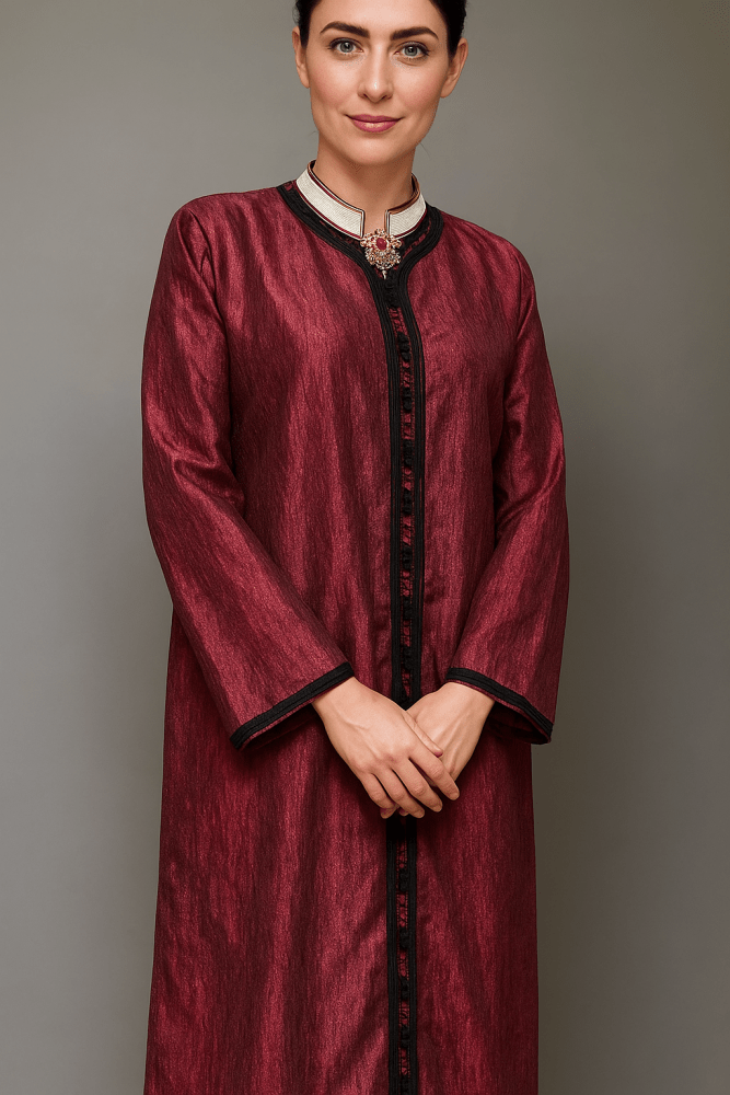 Woman wearing a burgundy traditional outfit with black trim against a gray background