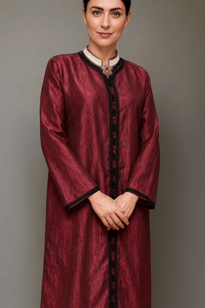 Woman wearing a burgundy traditional outfit with black trim against a gray background