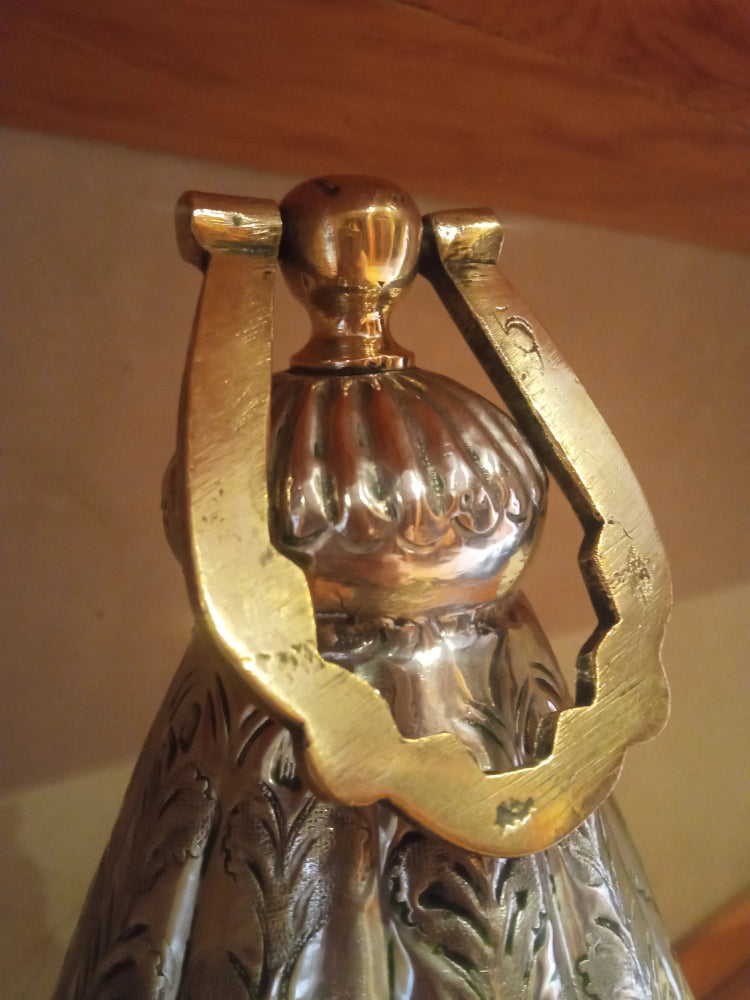 Decorative metal object with intricate design and brass accents on a wooden surface.