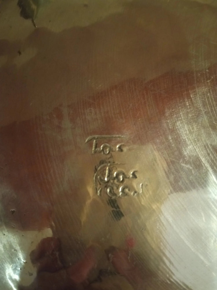 Close-up of a textured surface of moroccan vintage silver tagine 
with a brand logo in the center.